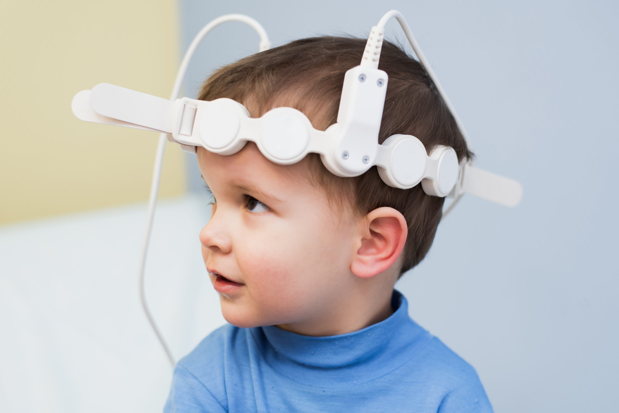 Child looking off camera with a magnetotherapeutic device on his head.