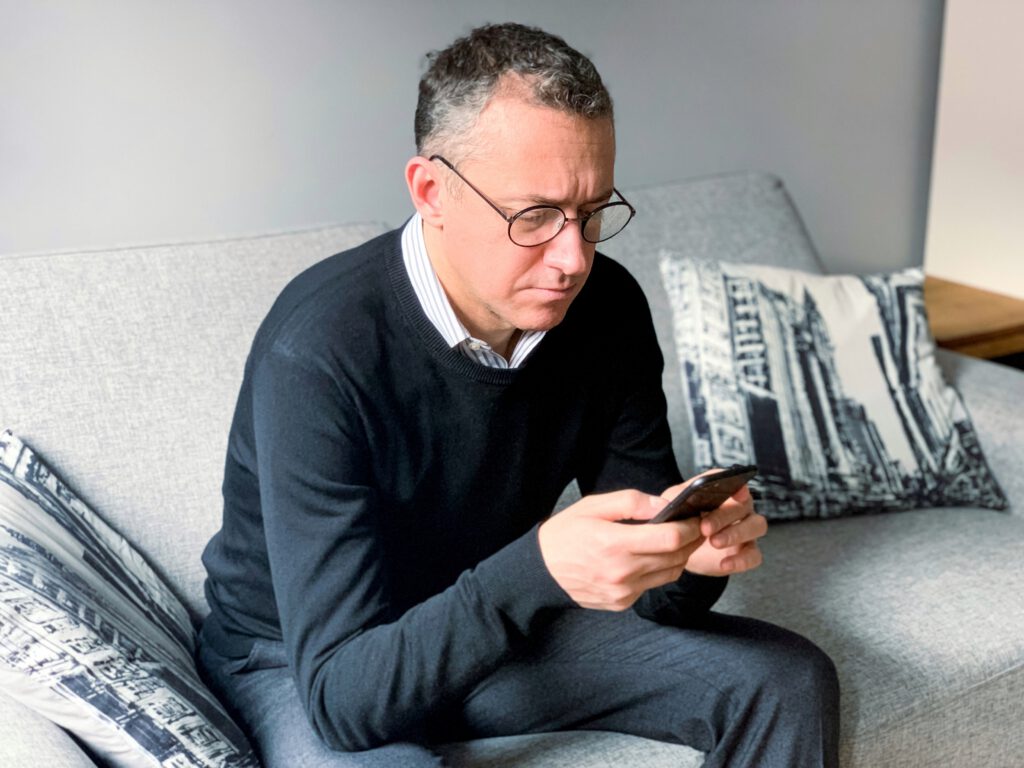 Man sitting on couch looking at phone.