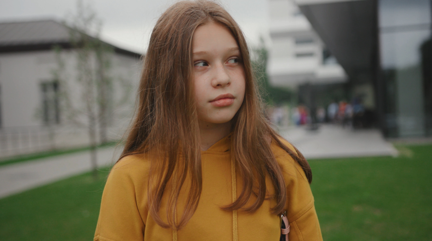 A child walking outside looking to the right.
