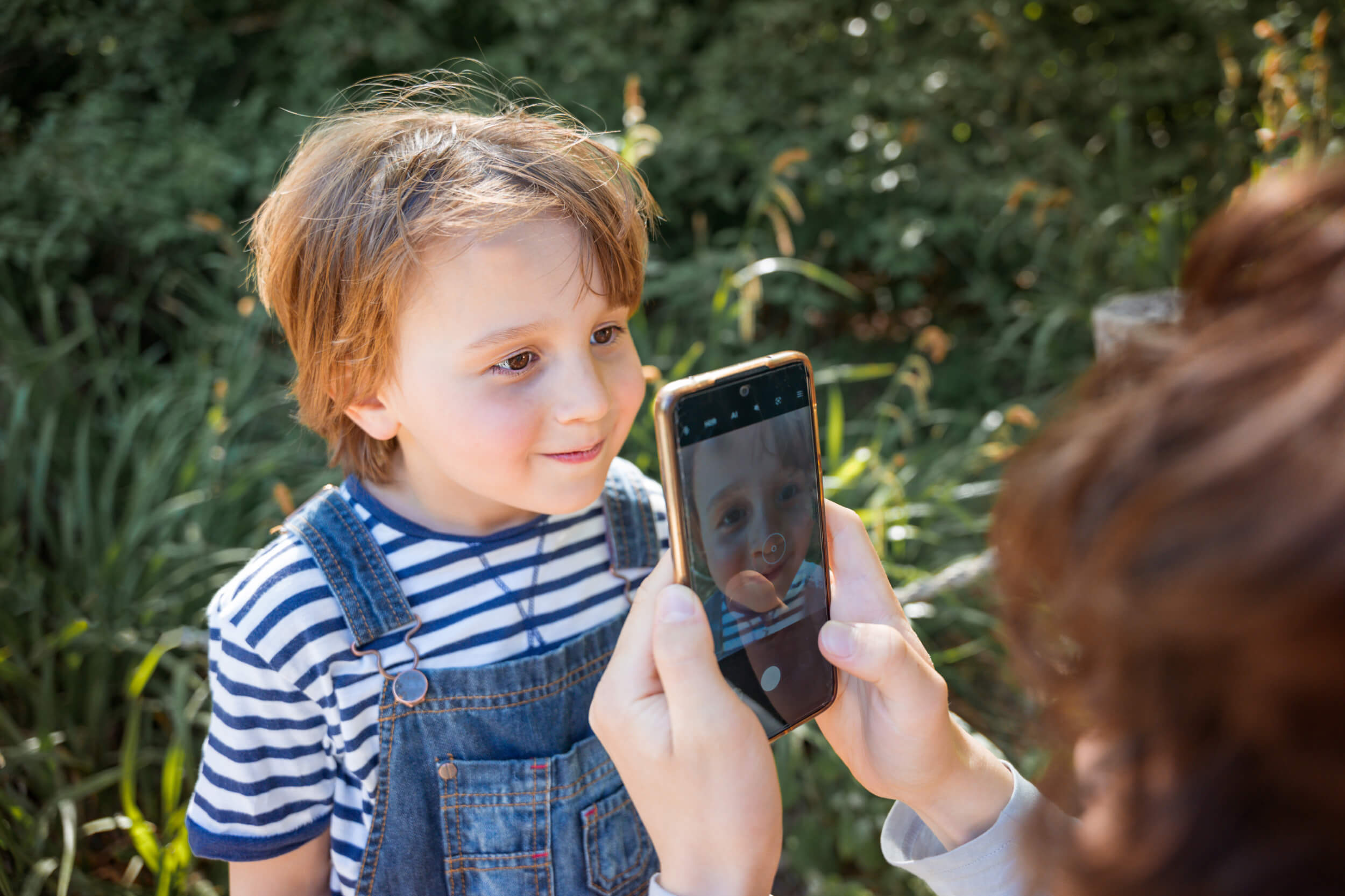 Child smiling at a phone with a camera open on the screen.