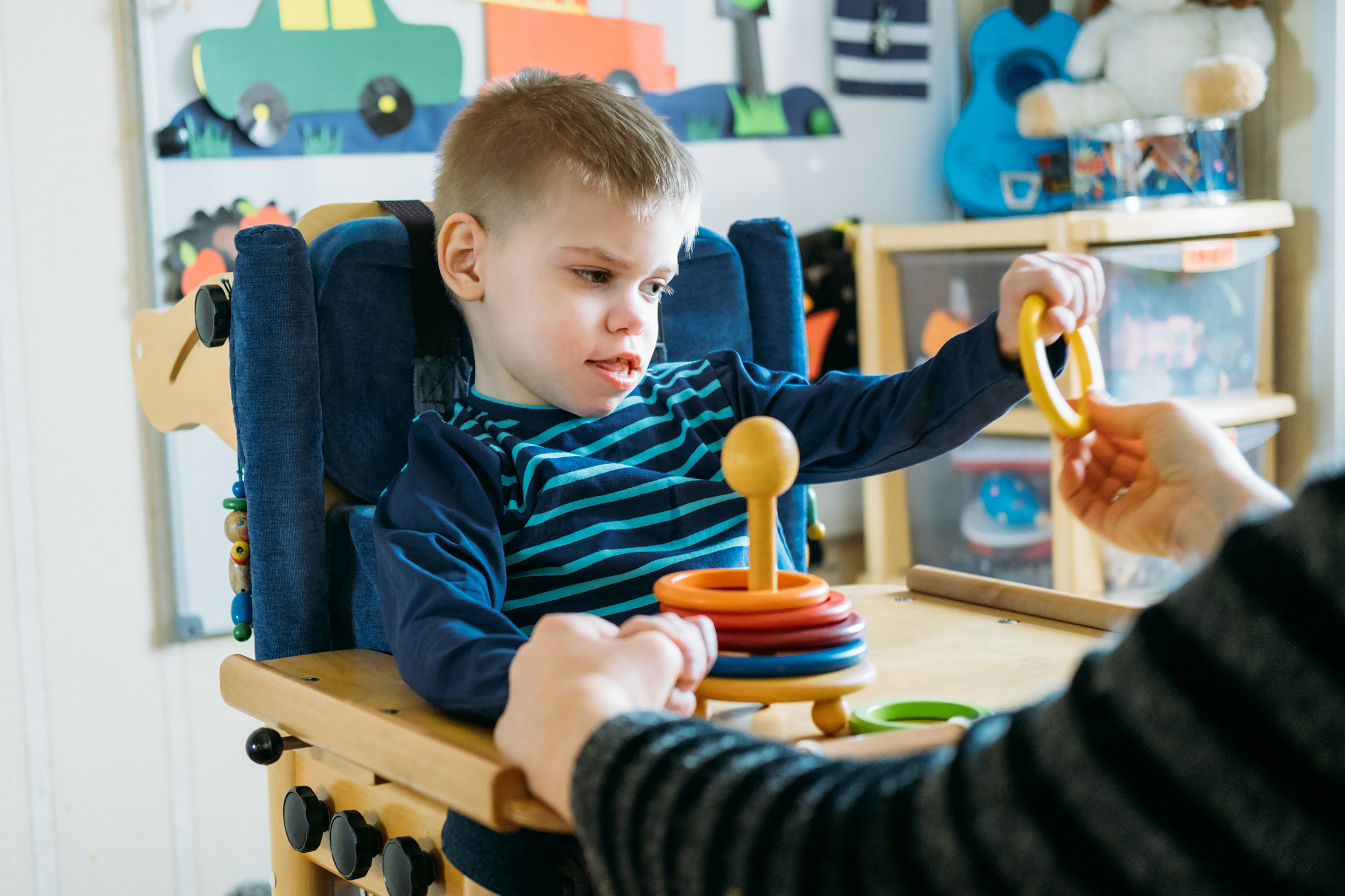 Boy with with Cerebral Palsy in special chair play with mom at home
