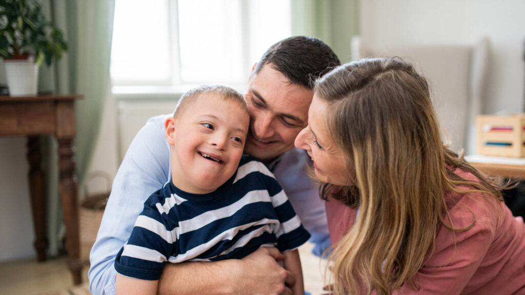 Two parents looking at a child sitting on the father's lap.